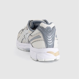 Asics trainer in cream and smoke grey, rear three-quarter view showing mesh upper, silver overlays, and white chunky sole