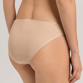 Model wearing Hanro brief in beige, smooth fabric with contrast trim, shown from rear three-quarter view