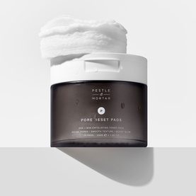 Pestle & Mortar Pore Reset Pads exfoliating treatment in dark jar with white lid, one pad displayed on top showing texture.