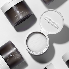 Pestle & Mortar Pore Reset Pads exfoliating treatment pads in dark grey jar, one open revealing textured white pads with spatula