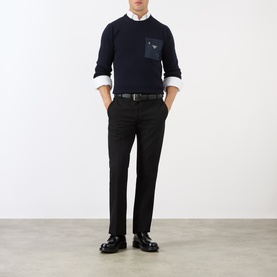 Model wearing Prada Gabardine Tailored Trousers in black, slim-leg with pressed creases, styled with navy crew-neck jumper and loafers.