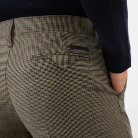 Model wearing Prada Houndstooth Check Trousers in Military, showing buttoned back welt pocket detail and sartorial logo label. Styled with navy