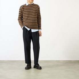 Model wearing Prada rust striped wool crew neck jumper with white shirt, black trousers and chunky black loafers.
