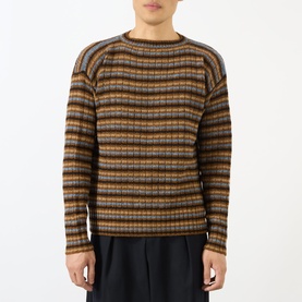 Model wearing Prada rust wool crew neck jumper in multicolour horizontal stripe pattern, styled with dark tailored trousers