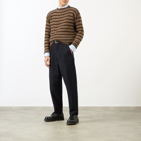 Model wearing Prada rust wool crew neck jumper with brown stripe pattern, styled with navy trousers and black leather shoes