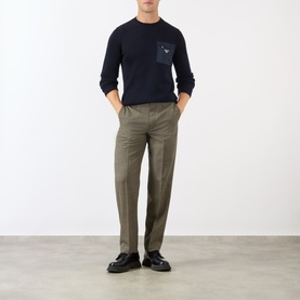Model wearing Prada Triangle Logo Patch Pocket Sweater in blue wool knit with crew neck, styled with olive trousers and black loafers.