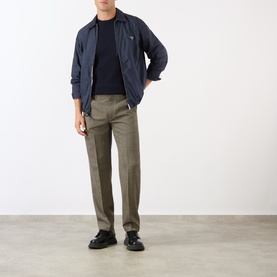 Model wearing Prada Triangle Logo Patch Pocket Sweater in blue, styled with a navy jacket, khaki trousers, and black loafers.