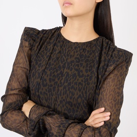 Model wearing Rotate dress in Mole Comb. 3088 leopard print, sheer long sleeves with structured shoulders, arms crossed.