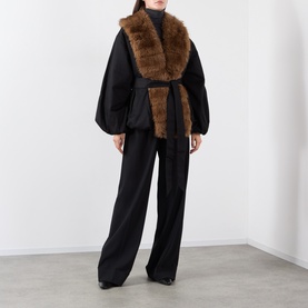 Model wearing Rotate black belted jacket with brown faux fur collar, styled with matching wide-leg black trousers.