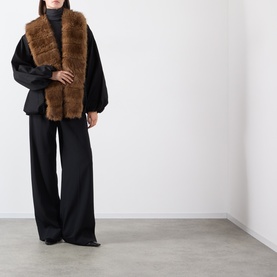 Model wearing Rotate black jacket with brown faux fur collar trim, styled with wide-leg black trousers