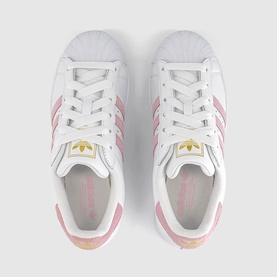 Adidas Superstar trainers in white with clear pink leather stripes, gold foil logo, white laces, overhead flat-lay view.
