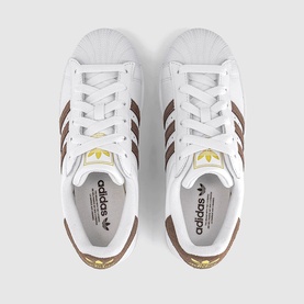 Adidas Superstar trainers in white with brown stripes, gold logo detailing and white shell toe, overhead view