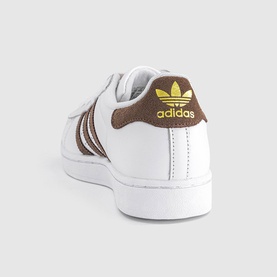 Adidas trainer in white and earth brown, featuring brown three-stripe detail, gold Trefoil logo, and white rubber sole.