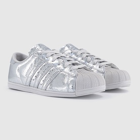 Adidas Superstar trainers in silver metallic, featuring three-stripe detailing, crinkle texture upper, and white shell toe sole.