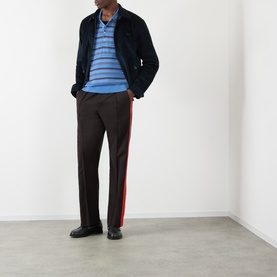 Model wearing Wales Bonner Drew Logo Corduroy Jacket in navy, styled with blue striped polo, dark brown wide-leg trousers with red side stripe