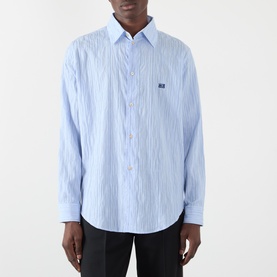 Model wearing Wales Bonner Atlantic Logo Striped Shirt in cornflower blue with white stripes, point collar, front button fastening, styled with black