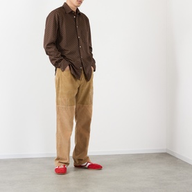 Model wearing Wales Bonner brown/caramel polka dot casual shirt, styled with tan wide-leg trousers and red loafers.