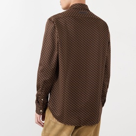 Model wearing Wales Bonner casual shirt in brown and caramel geometric print, long-sleeved, styled with mustard trousers, rear view.
