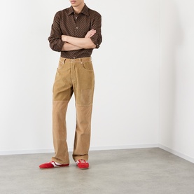 Model wearing Wales Bonner brown caramel printed casual shirt, styled with tan corduroy trousers and red loafers, arms crossed.