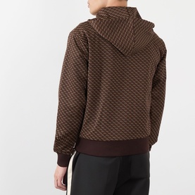 Model wearing Wales Bonner brown and caramel geometric-jacquard hoodie, rear view, styled with dark trousers featuring side stripe.