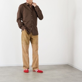 Model wearing Wales Bonner camel cotton chinos, styled with a brown patterned shirt and red loafers.