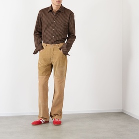 Model wearing Wales Bonner camel cotton chinos, styled with a brown patterned shirt and red loafers.