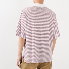 Model wearing Wales Bonner polo in ivory and wine stripe, back view, short sleeves, with tan trousers