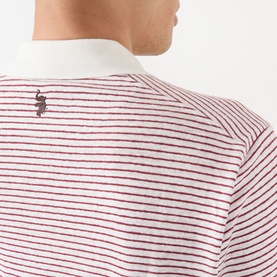 Model wearing Wales Bonner polo in ivory and wine stripe, close-up of back showing small logo embroidery and white collar detail.
