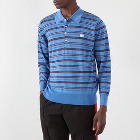 Model wearing Wales Bonner Beam Logo Striped Polo Sweater in Chambray Blue, long sleeves, ribbed trims, paired with dark trousers