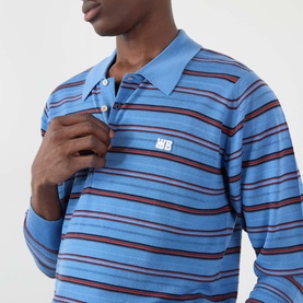 Model wearing Wales Bonner Beam Logo Striped Polo Sweater in Chambray Blue, long-sleeve knit with contrast stripe detail and logo embroidery at chest.