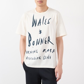 Model wearing Wales Bonner ivory cotton T-shirt with large navy handwritten graphic lettering across the chest and body.