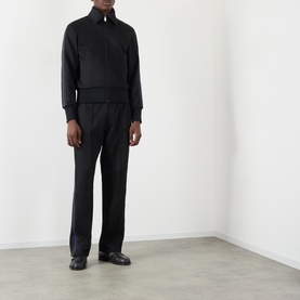 Model wearing Wales Bonner Form Logo Zip Track Sweatshirt in black with contrast arm stripe detailing, styled with black tailored trousers and
