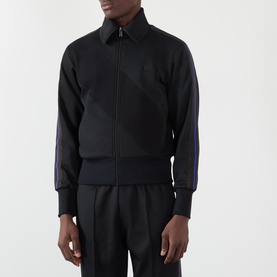 Model wearing Wales Bonner Form Logo Zip Track Sweatshirt in black with purple contrast arm stripes, logo embroidery, and matching trousers.