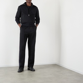 Model wearing Wales Bonner Form Logo Zip Track Sweatshirt in black with matching black trousers and black loafers.