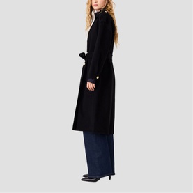 Model wearing Maje red long coat with tie belt, styled with dark wide-leg jeans and black heels, side view