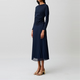 Model wearing Claude Pierlot blue long-sleeve midi dress with pleated skirt, styled with gold block-heel sandals