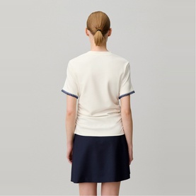 Model wearing Claude Pierlot cream short-sleeve top with contrast trim cuffs, styled with a navy mini skirt, rear view.
