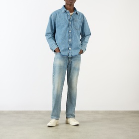 Model wearing AMI Bleu Used denim casual jacket with matching jeans and cream trainers