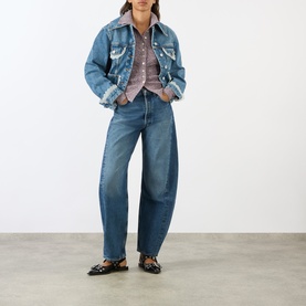Model wearing AgoldE proof-wash wide-leg jeans in mid blue denim, styled with a denim jacket, check shirt and black loafers.
