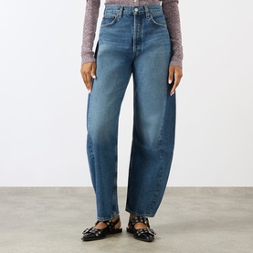 Model wearing AgoldE Jeans in proof blue, relaxed barrel-leg fit, high waist, 100% cotton denim, styled with black Mary Jane flats