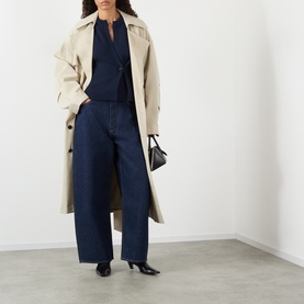 Model wearing AgoldE rinse wide-leg jeans in dark indigo denim, styled with beige trench coat, navy top and black heeled mules