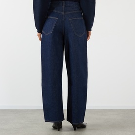 Model wearing AgoldE rinse wide-leg jeans, rear view, styled with black heeled mules and navy knit top