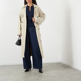 Model wearing AgoldE rinse wide-leg jeans in dark denim, styled with a beige trench coat, navy top, and black heeled boots and bag