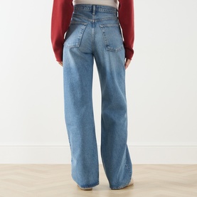 Model wearing AgolDe straight-leg jeans in outbreak blue denim, wide-leg silhouette, rear view, styled with red knit top