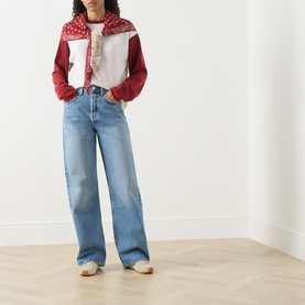 Model wearing AgoldE straight jeans in outbreak, styled with a red and white varsity jacket and cream shoes.