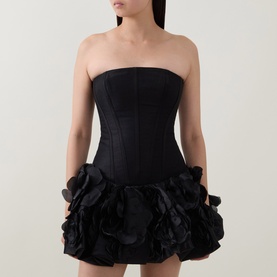 Model wearing Aje black strapless mini dress with structured corset bodice and layered floral appliqu&eacute; skirt in linen blend.