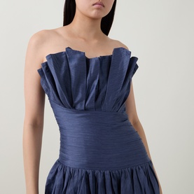 Model wearing Aje navy strapless dress with pleated ruffle bodice and gathered skirt, in lyocell-linen blend