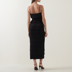 Model wearing Aje black tiered fringe midi dress with spaghetti straps, shown from the back, styled with black heeled mules
