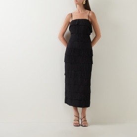 Model wearing Aje black polyester midi dress with tiered ruffle detail, thin straps, and fitted silhouette, styled with black strappy heels