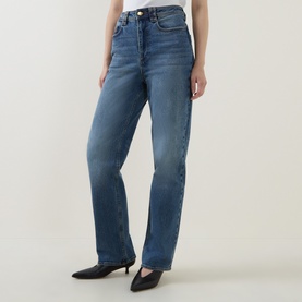 Model wearing Aje jeans in Stormy Wash, high-rise straight-leg cut, styled with black kitten heel mules.